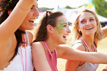 Three girl friends laughing at a music festival