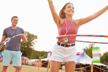 Man and woman dancing with hula hoops at a music festival - obrazy, fototapety, plakaty
