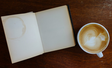 open blank old notebook on wooden table with hot coffee