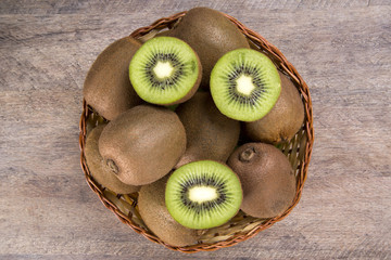 Some kiwis in a basket over a wooden surface