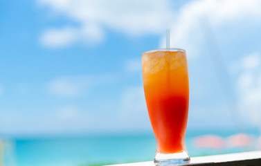 The Caribbean lifestyle symbol, Caribbean Cocktail bright orange against blurred sea and sky background.