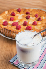 Cake with fresh  raspberry  and a peach milkshake closeup on a wooden table.