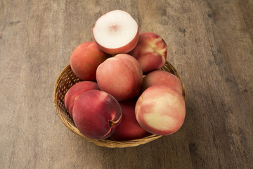 Some peaches in a basket over a wooden surface