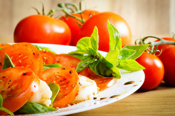 Teller mit Tomaten und Mozarella auf einem Holztisch, close up