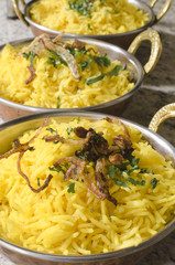 Yellow rice with fried onion in bowls in kitchen restaurant.