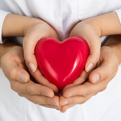 Woman and man holding red heart together