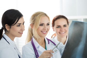 Portrait of three smiling female medicine doctors  looking at x-