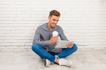 man sitting on the floor with digital tablet and coffee