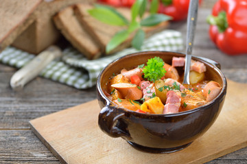 Kräftiges Kartoffelgulasch mit Speck und Wiener Würstchen in der Keramikschale