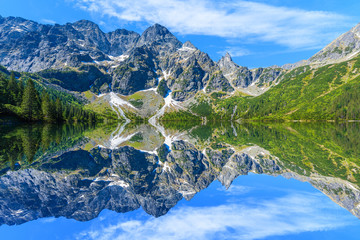 Reflection of mountain peaks in beautiful green water Morskie Oko lake, Tatra Mountains, Poland - obrazy, fototapety, plakaty