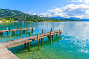 Wooden pier for mooring boats on Worthersee lake on beautiful summer day, Austria