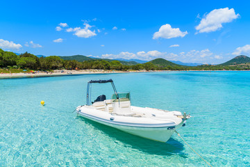 Fototapeta na wymiar White dinghy boat on crystal clear turquoise sea water of Santa Giulia beach, Corsica island, France
