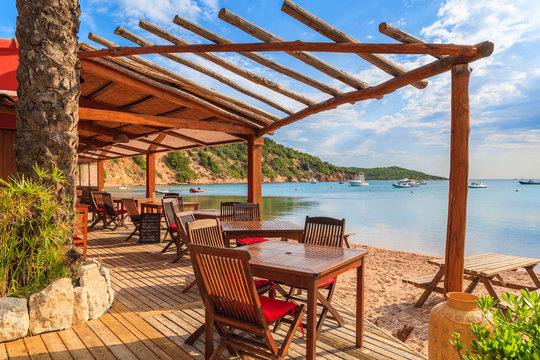 Fototapeta Chairs and tables in beach bar in Santa Manza bay, Corsica island, France