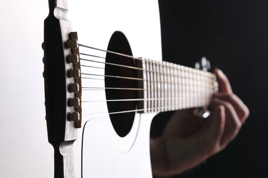 Acoustic guitar close-up with fingers playing it