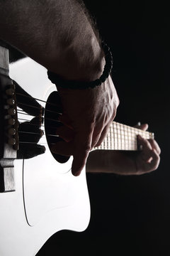 Acoustic guitar close-up with fingers playing it