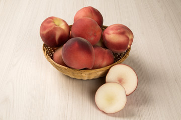 Some peaches in a basket over a white background