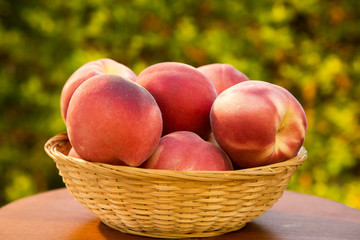 Some peaches in a basket over a wooden surface