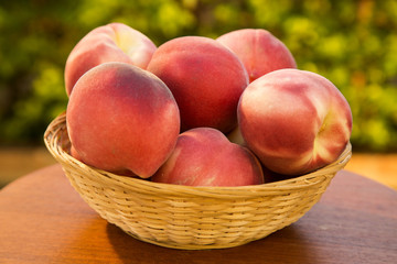 Some peaches in a basket over a wooden surface