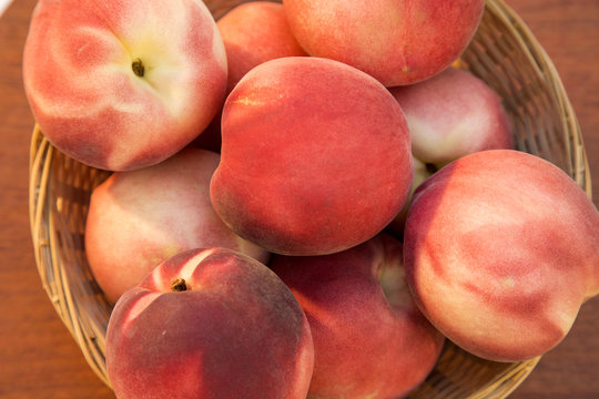 Some peaches in a basket over a wooden surface