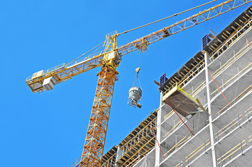 Fototapeta na wymiar Crane lifting concrete mixer container against blue sky