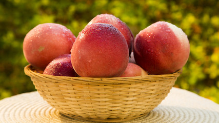 Some peaches in a basket over a wooden surface