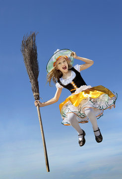 Happy Little Witch with a Broom flying high above the earth