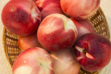 Some peaches in a basket over a wooden surface