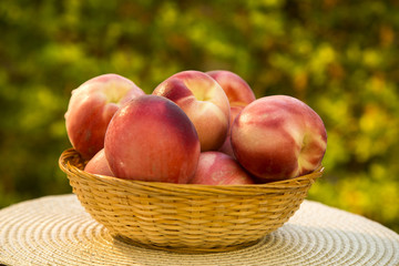 Some peaches in a basket over a wooden surface