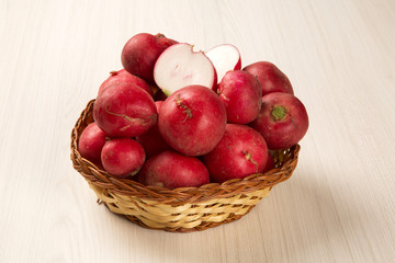 Some radishes in a basket over a white background