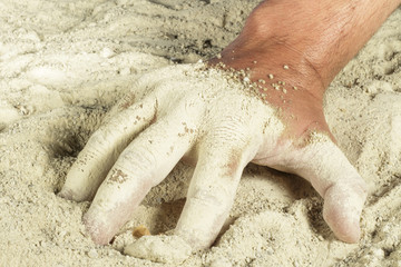 Man hand with fingers covered with white sand