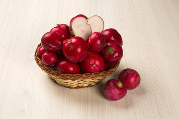 Some radishes in a basket over a white background
