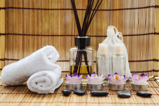 Spa stones, towels and candles shot front on on a bamboo mat and bamboo background
