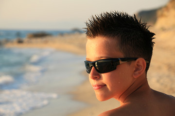 Portrait of young boy wearing sunglasses and posing by sea