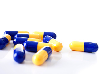 Tablets blue and yellow  scattered capsules shot front on on a white background