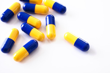 Tablets blue and yellow  scattered capsules shot from above on a white background