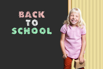 kleines Mädchen schreibt "Back to School" and Wandtafel