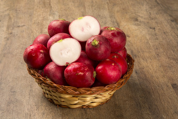 Some radishes in a basket over a wooden surface