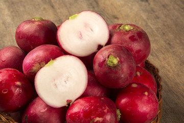 Some radishes in a basket over a wooden surface