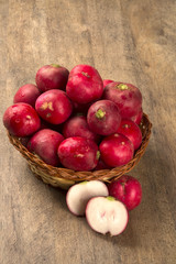 Some radishes in a basket over a wooden surface