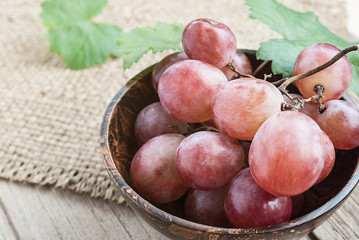 Red grape in wooden bowl on wooden table