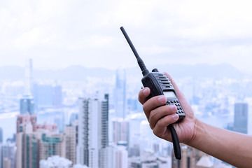 hand holding walky talky with cityscape as background