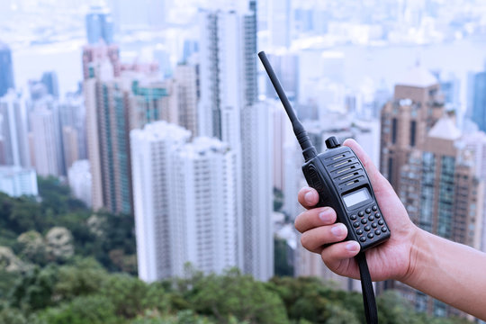 Hand Holding Walky Talky With Cityscape As Background