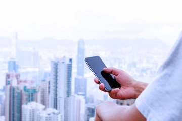 hand holding mobile phone with cityscape as background