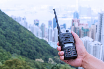 hand holding walky talky with cityscape as background © zhu difeng