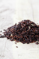Riceberry rice in a small pile on wooden table, Long grain rice, brown rice
