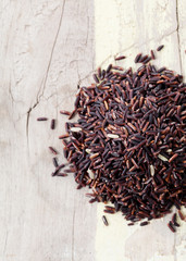 Riceberry rice in a small pile on wooden table, Long grain rice, brown rice