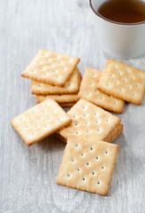 Stack of crackers and tea cup on wooden plate