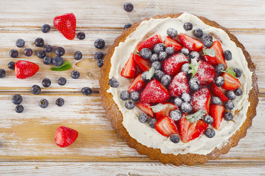 Cake with fresh berries on  wooden background.