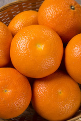 Some tangerines in a basket over a wooden surface