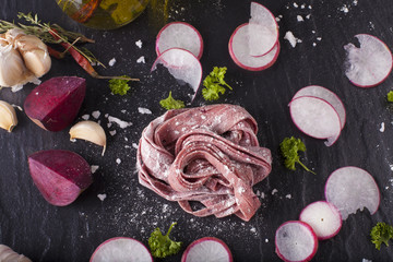 fresh beetroot pasta, fresh purple beetroot pasta tagliatelle on black stone decor background